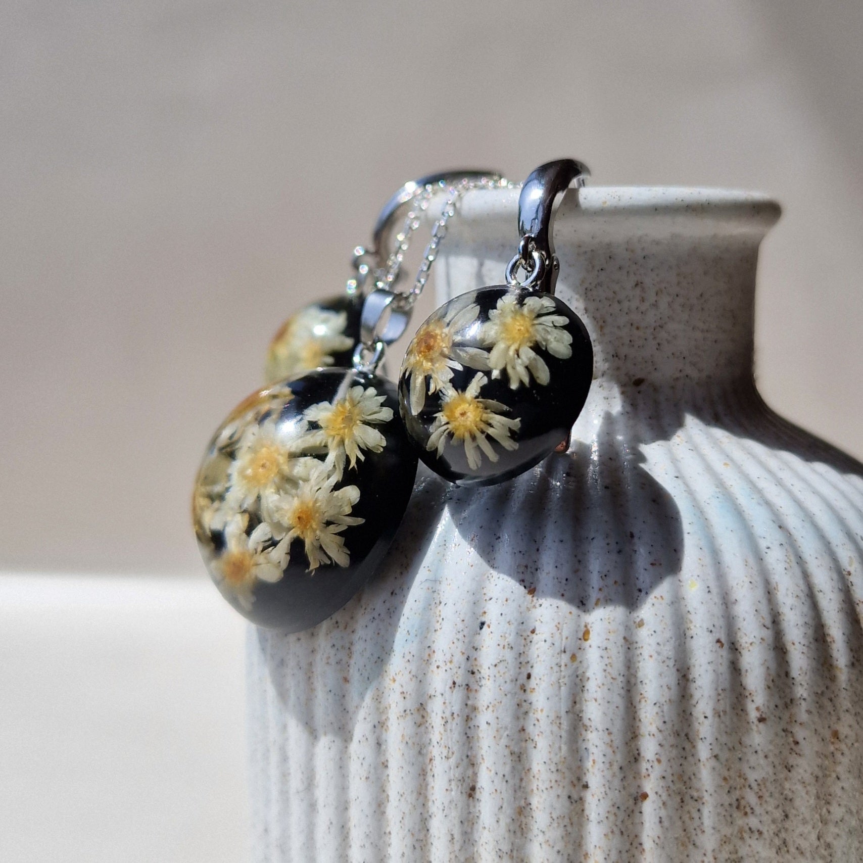 Small real chamomile flower background with black colored 925 silver jewelry set